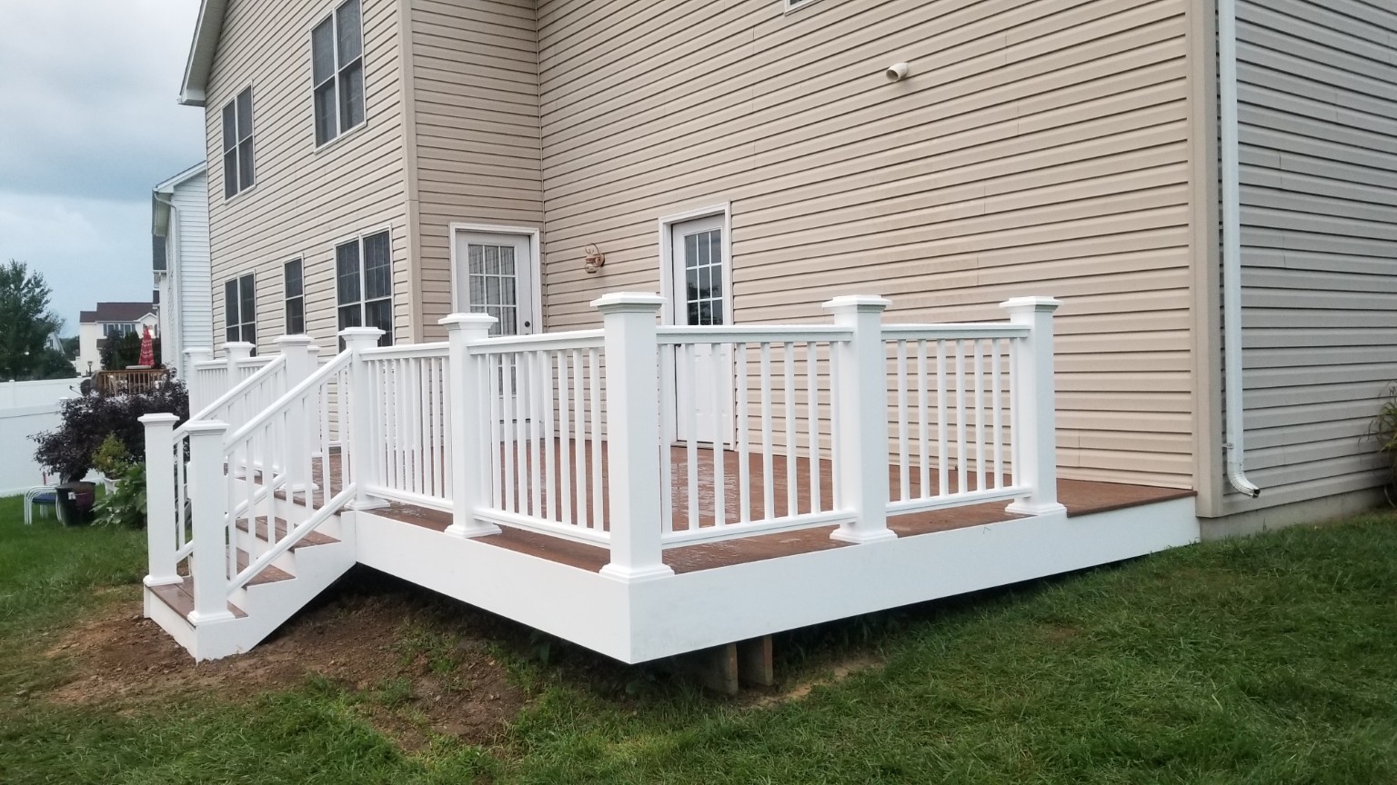 After: renovated deck with white railings, trim and stairs