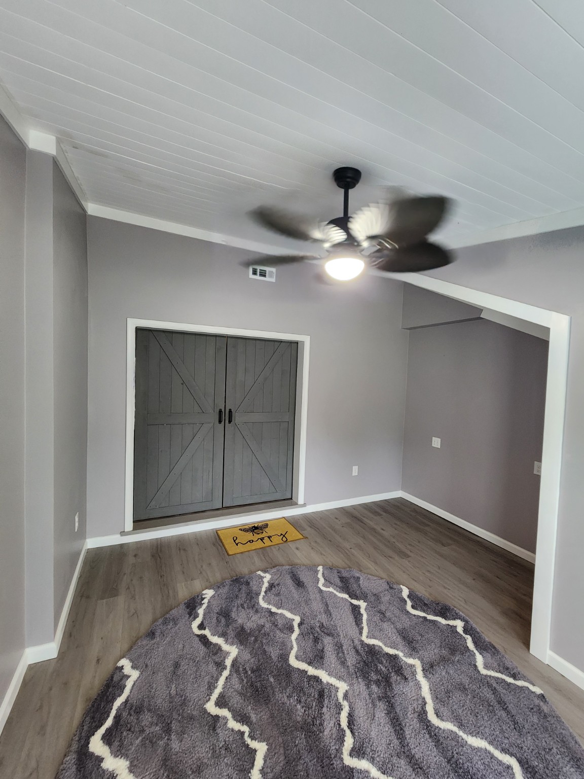 Finished sunroom interior with white ceiling, ceiling fan and barn-style doors