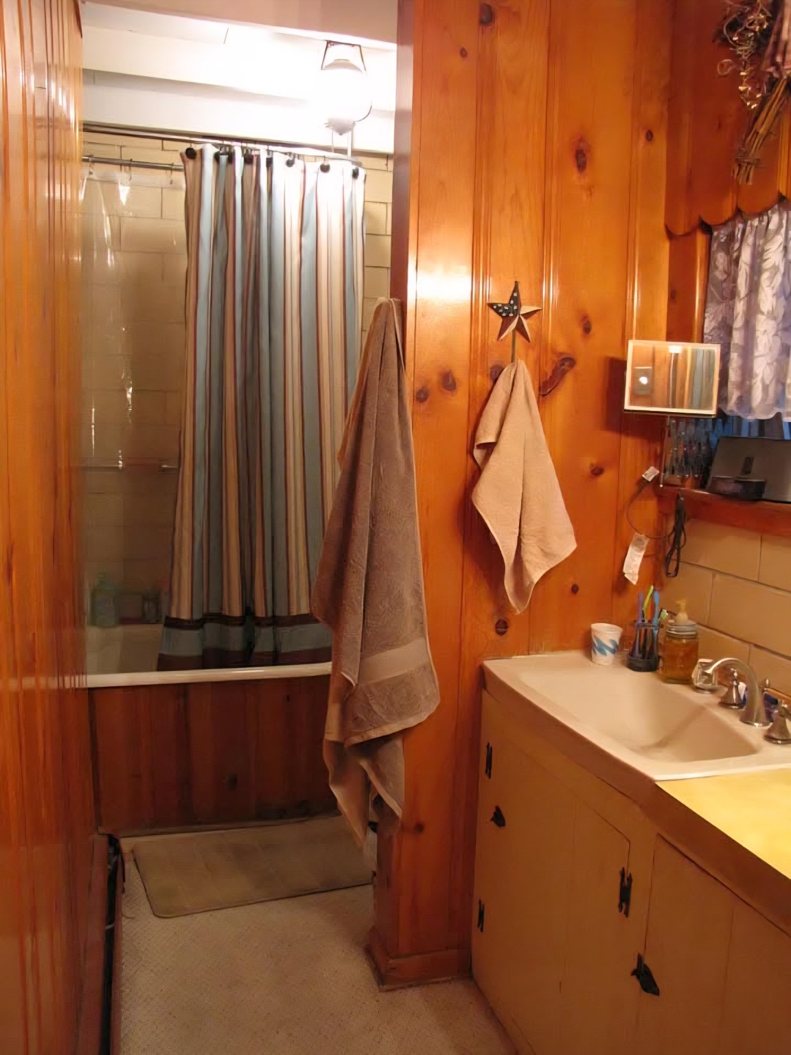 Before: wood-paneled bathroom with tub and vanity
