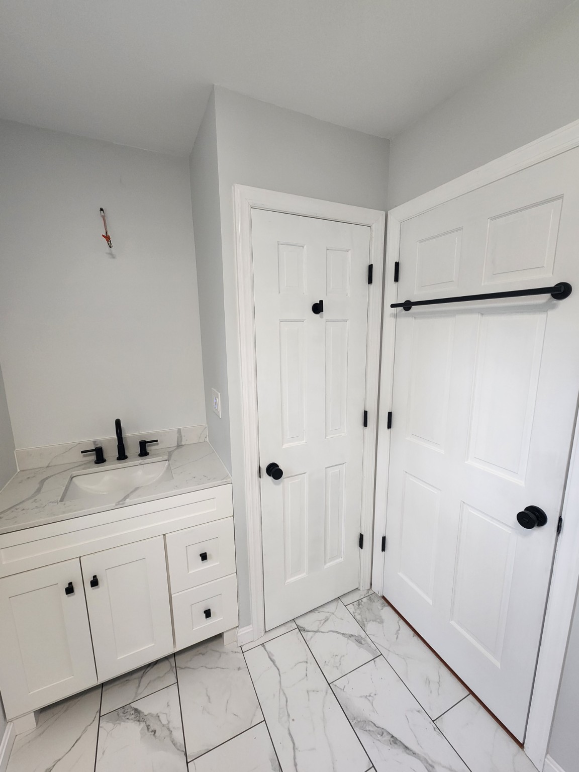 Renovated bathroom vanity, marble-look floor and white doors with black hardware
