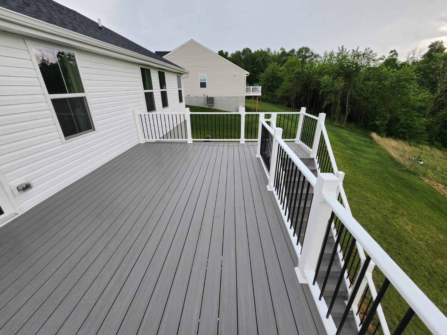 Finished gray deck surface and white railing with black balusters