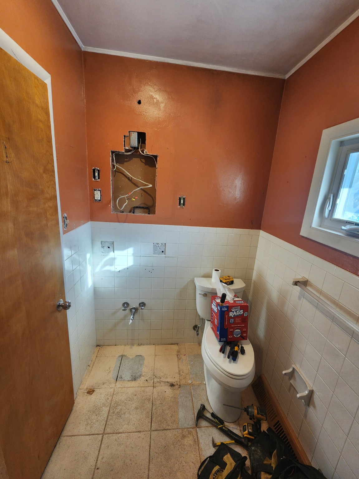 Before: orange bathroom with old wall tile and vanity removed