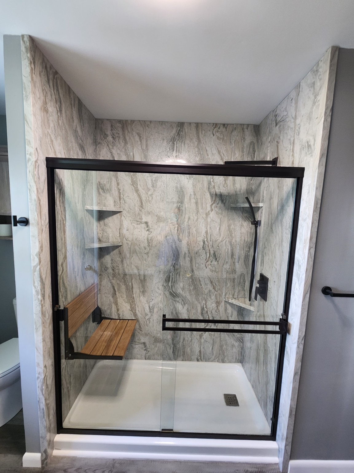 After: Tub-to-shower conversion with marble-look panels and folding seat