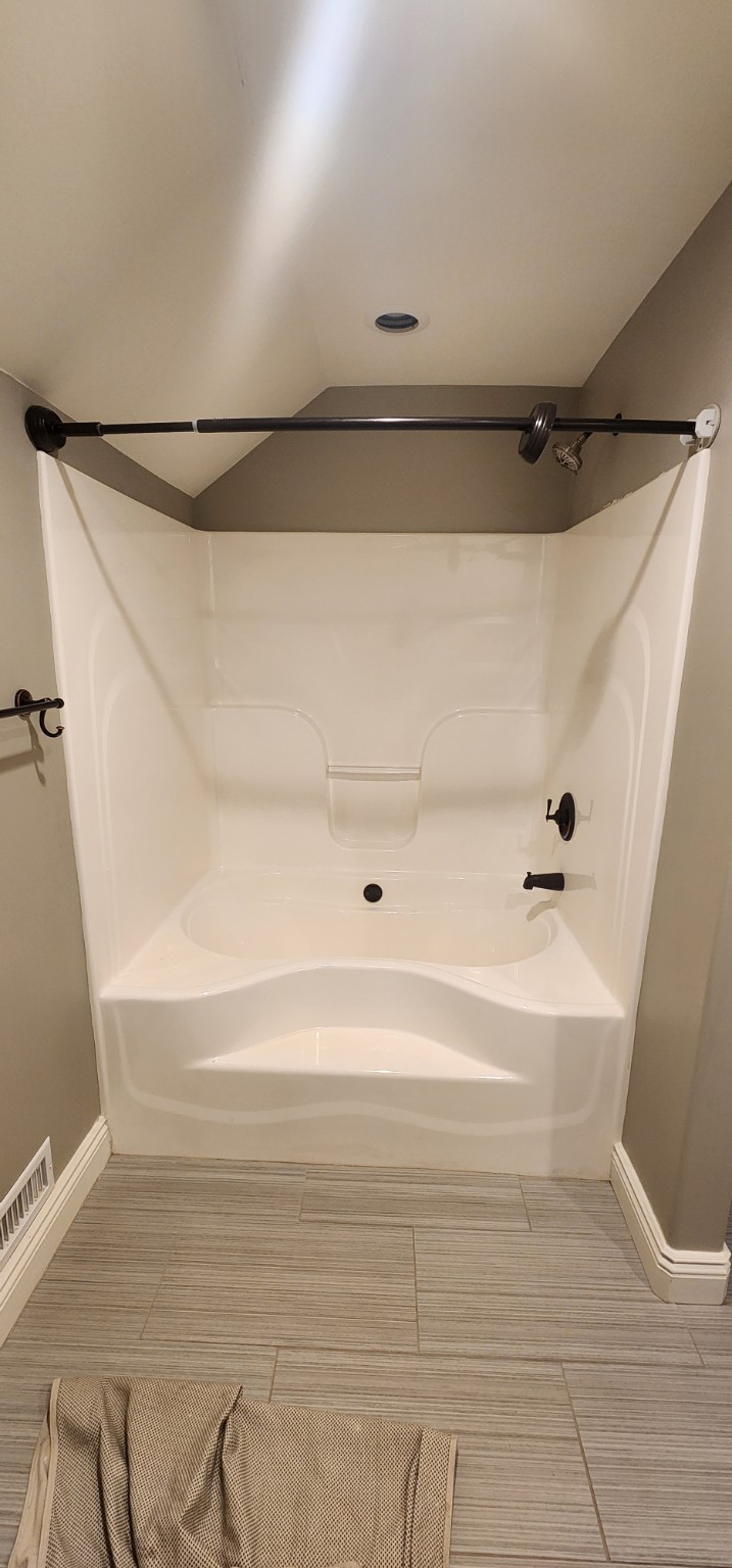 Before: bathtub and molded surround beneath a sloped ceiling