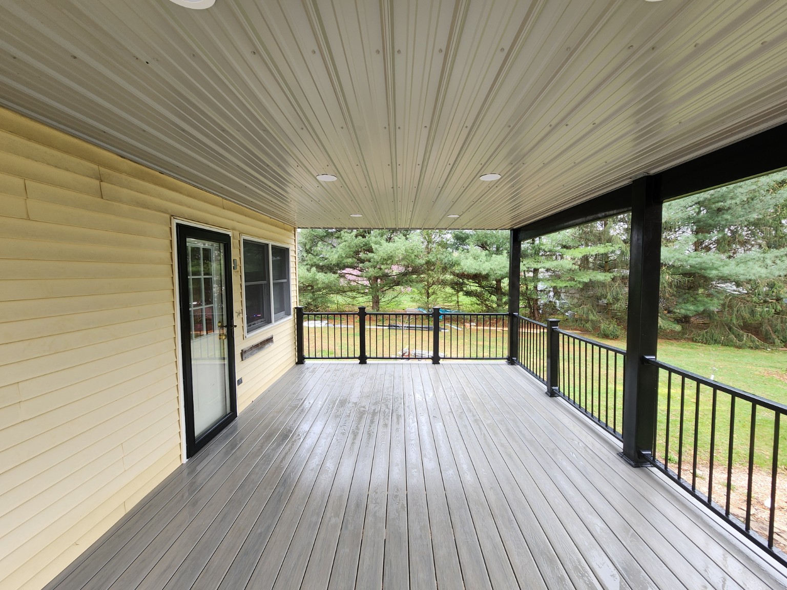 Finished covered porch with gray decking, black railings and recessed ceiling lights