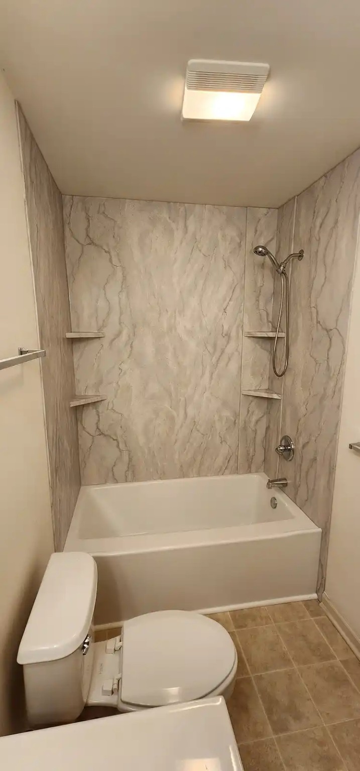 Bathtub with marble-look acrylic surround and corner shelves